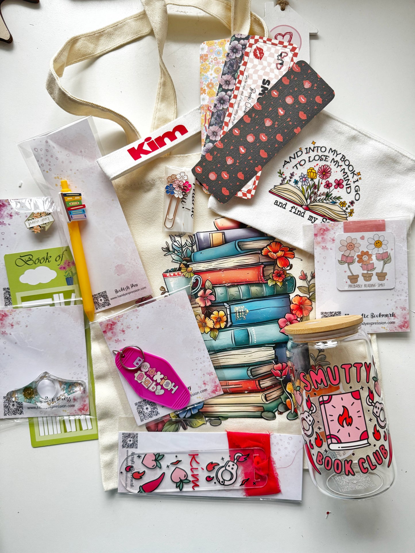 Collection of stationery items including notebooks, a glass jar, and decorative cards on a white surface.